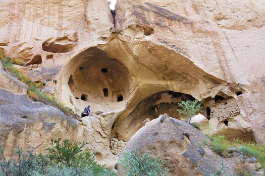 A young man, a tourist, climbs on the old ancient residential caves of Cappadocia, carved out of the mountain from sandstone.