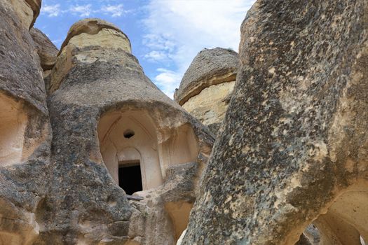 View of the ruins of monastic cells felled in a sandstone mountain range in the valley of Cappadocia against a blue sky