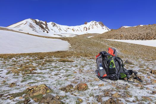 Backpacks of tourists are located on the trail at the foot of Erciyes mountain against the background of a clear blue sky.