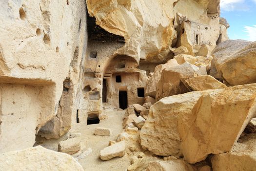 Mysterious inconspicuous entrance among stone boulders in the ancient cave temple, carved in the mountain valley of Cappadocia