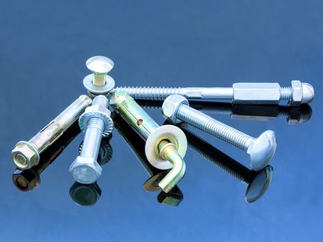 Various equipment: screw bolts and bolts with washers on a glossy dark blue surface of a metal background design.