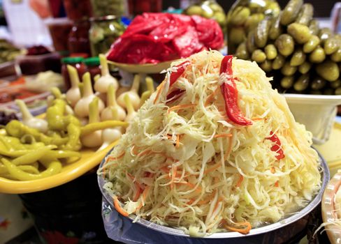 A close-up of lettuce made from sauerkraut, carrots and sweet peppers against other fermented vegetables in a blur is an excellent recipe for healthy and tasty food.