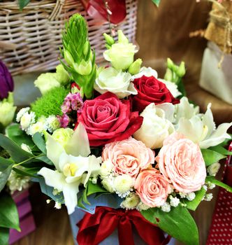 Closeup of beautiful bouquet of fresh red, pink and white rose in bloom against a wicker basket in blur