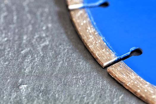 Segment of a diamond blue cutting disc on a background of gray concrete close-up with a place for copy space.