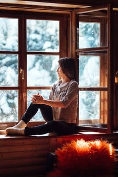 girl in the house near the window overlooking a snowy landscape