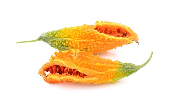 Two overripe bitter melon fruits with orange and green skin, splitting open to show red seeds inside, isolated on a white background