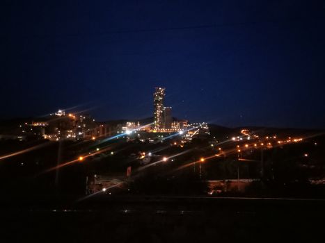 A large cement factory, kind of at night, lamps are lit.
