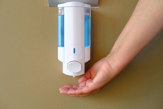 Closeup of Female hand using alcohol gel disinfecting hands. Cleaning Hands. Washing hands using automatic sanitizer dispenser.  