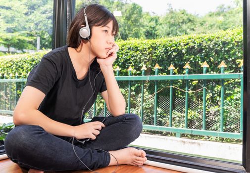 Happy teenage female  learning to the music from smartphone in room at home