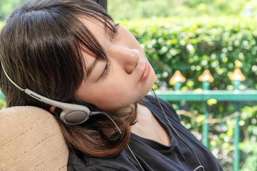 Teenage female with headphones and listening to music from mobile phone  at home