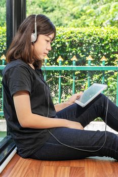 Happy girl listening to the music from a digital tablet in room at home