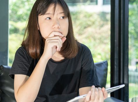 Student teenage studying online from digital tablet on the sofa at home