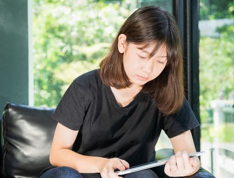 Student teenage studying online from digital tablet on the sofa at home