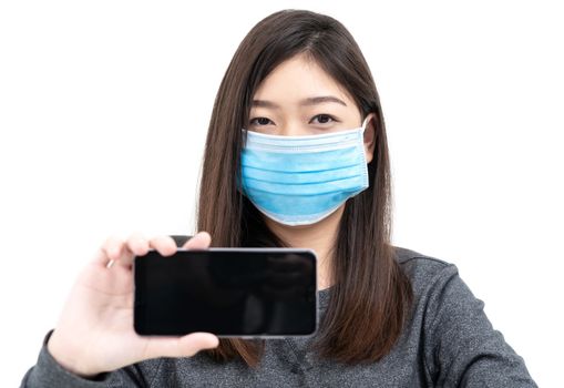 Close up woman wearing protective mask holding and showing mobile phone with blank black screen on white background