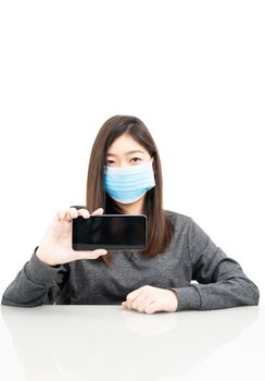 Close up woman wearing protective mask holding and showing mobile phone with blank black screen on white background