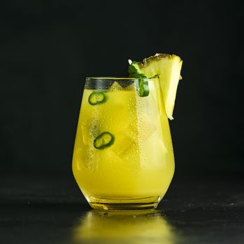 Spicy pineapple jalapeno mezcalita or margarita for Cinco de Mayo is a refreshing cocktail made with pineapple, cilantro, jalapeno and mexican distilled alcoholic beverage on black surface