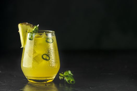 Spicy pineapple jalapeno mezcalita or margarita for Cinco de Mayo is a refreshing cocktail made with pineapple, cilantro, jalapeno and mexican distilled alcoholic beverage on black surface