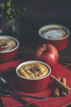 Three apple pies in ceramic baking molds with red napkin ramekin on dark wooden table. Close up, shallow depth of the field.