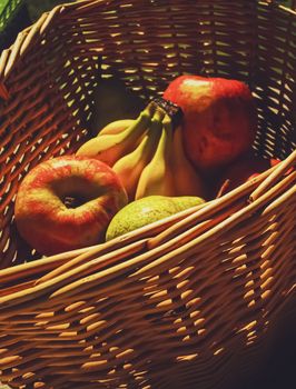 Organic apples, pears and bananas on rustic in a wicker basket, fruits farming and agriculture