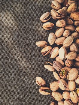 Pistachio nuts on rustic linen background, food and nutrition