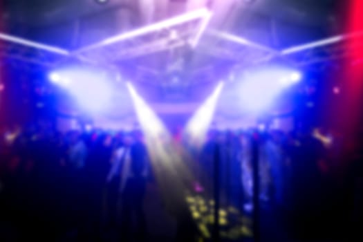 Lights in the club at midnight. Crowd of people at party. Motion blurred picture.