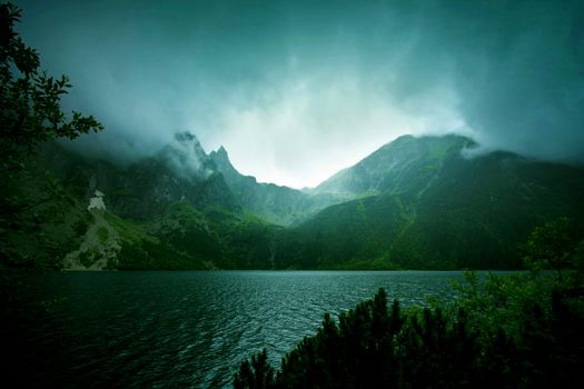 Fog and dark clouds in mountains. Lake in mountains.