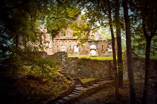 Abandoned place. Castle ruins in the green forest.