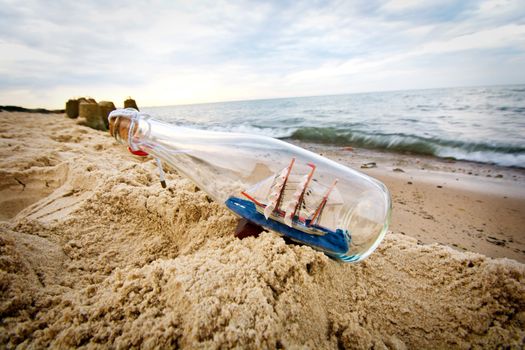 Bottle with ship inside lying on the beach. 