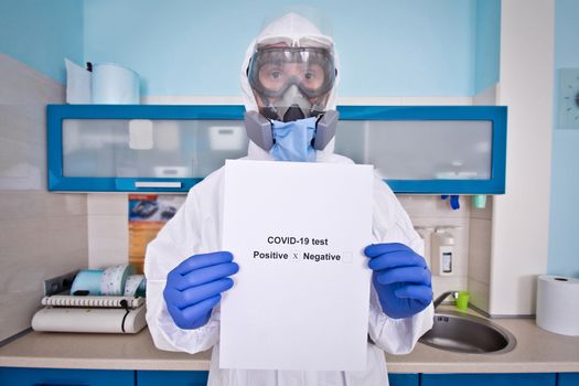Doctor in protective suit uniform and mask holds coronovirus test results. Coronavirus outbreak. Covid-19 concept.