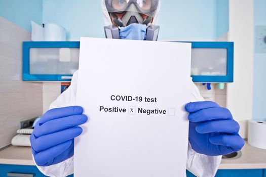 Doctor in protective suit uniform and mask holds coronovirus test results. Coronavirus outbreak. Covid-19 concept.