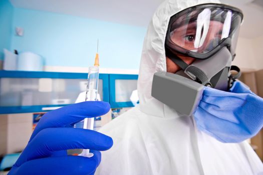 Doctor in protective suit uniform and mask holds injection syringe with vaccine. Coronavirus outbreak. Covid-19 concept.