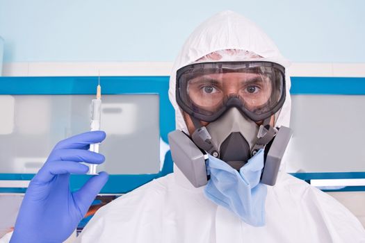 Doctor in protective suit uniform and mask holds injection syringe with vaccine. Coronavirus outbreak. Covid-19 concept.