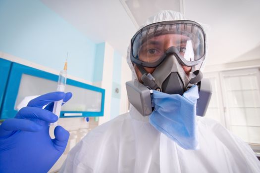 Doctor in protective suit uniform and mask holds injection syringe with vaccine. Coronavirus outbreak. Covid-19 concept.