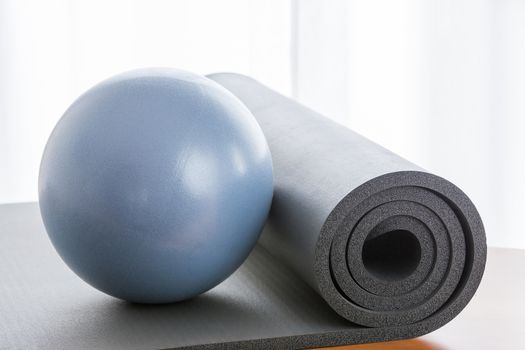 A blue ball and a grey pilates mat, with a back light and a wooden floor