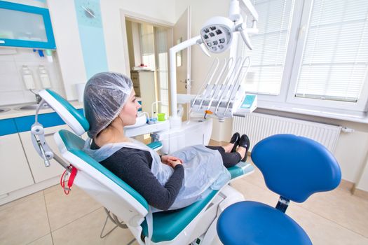 Female patient waiting for dental treatment in a dental chair. Dental Hygiene and Health conceptual image.