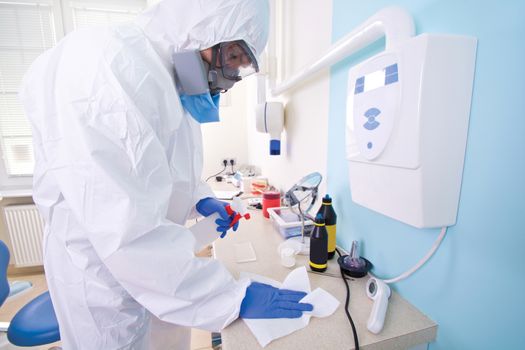 Doctor in protective suit uniform and mask cleans the laboratory. Coronavirus outbreak. Covid-19 concept.