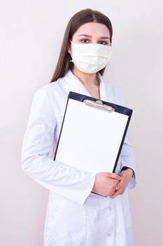 Female doctor wearing protection face mask holding notes. Free copy space. Covid-19 concept.