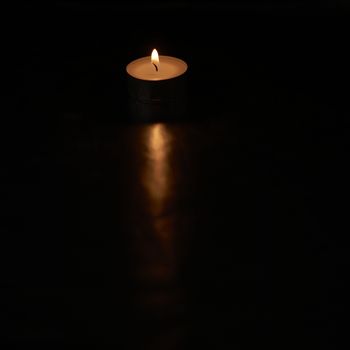 Small burning candle on black background, darkness, black, trail of light