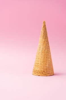 An upside down wheat flour ice cream cone on a pink background. Summer concept.