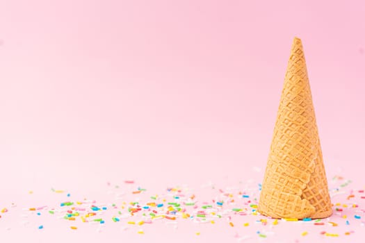 An upside down wheat flour ice cream cone located to the right on a pink background. Summer concept.