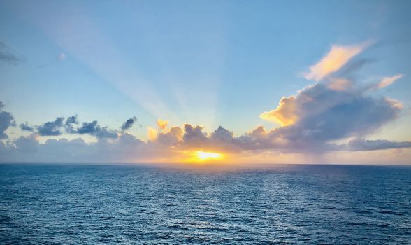 Romantic sunset over the ocean. Sunbeams passing through the clouds. Vivid colors horisontal shot