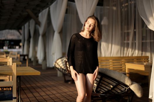 portrait of young girl in black jacket sweater at sunset, summer interior