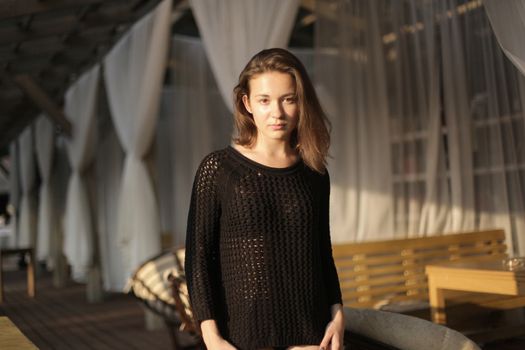 portrait of young girl in black jacket sweater at sunset, summer interior