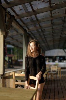 portrait of young girl in black jacket sweater at sunset, summer interior