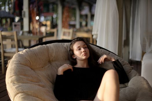 portrait of young girl in black jacket sweater at sunset, summer interior