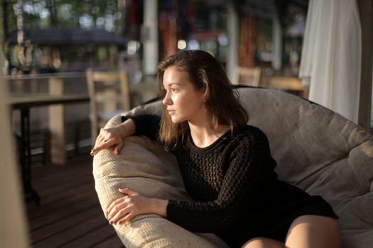 portrait of young girl in black jacket sweater at sunset, summer interior