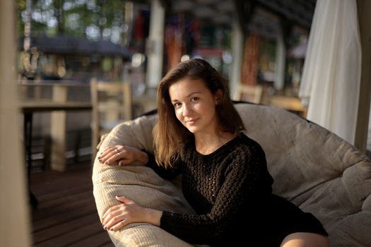 portrait of young girl in black jacket sweater at sunset, summer interior