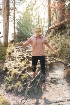 Active sporty woman running in autumn fall forest jumping over the roots on the path. Healthy lifestyle image of young active caucasian woman jogging outside in nature.
