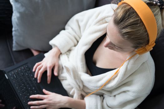 Stay at home, shelter in place and social distancing. Woman in her casual home bathrobe relaxing while working remotly from her living room. Using social media apps for video chatting.