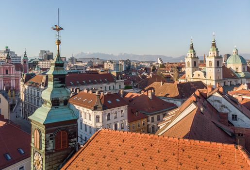 Scenic panoramic aerial drone view of rooftops of medieval city center, town hall and cathedral church in Ljubljana, capital of Slovenia, at sunset.